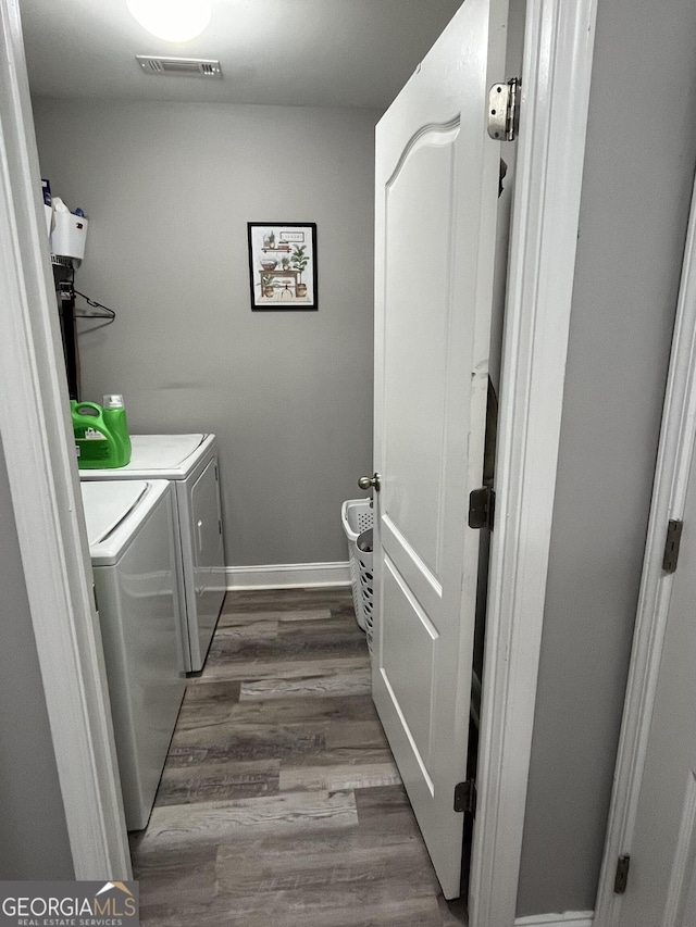 washroom with washing machine and dryer and hardwood / wood-style flooring