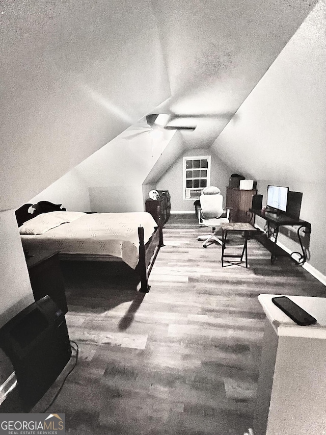 bedroom with ceiling fan, vaulted ceiling, wood-type flooring, and a textured ceiling