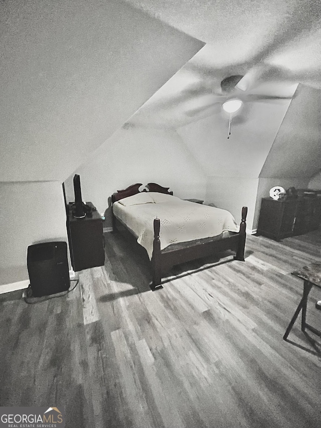 bedroom with lofted ceiling, wood-type flooring, a textured ceiling, and ceiling fan