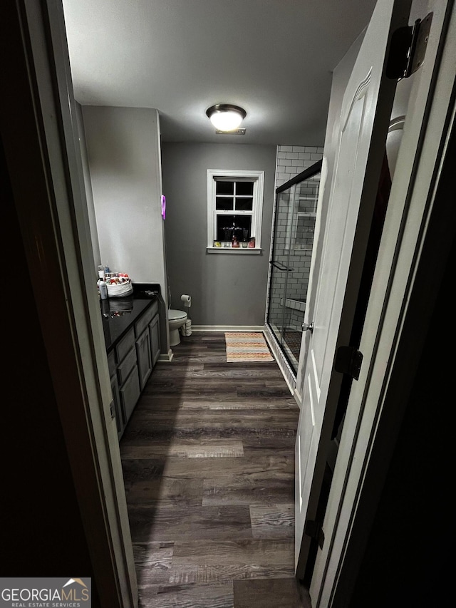 bathroom featuring vanity, toilet, a shower with door, and hardwood / wood-style flooring