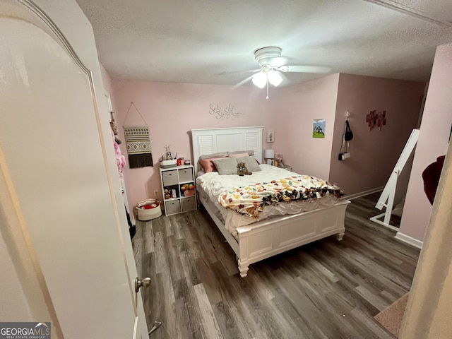 bedroom with ceiling fan, dark wood-type flooring, and a textured ceiling