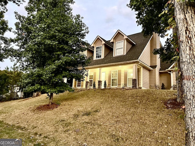 cape cod house featuring a front yard