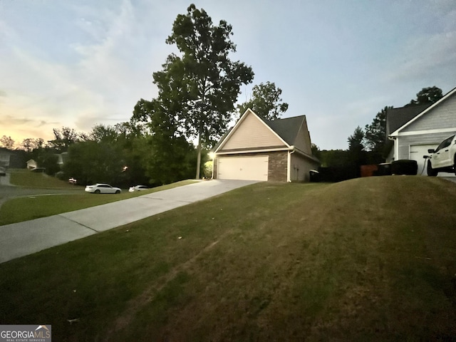 property exterior at dusk with a garage and a lawn