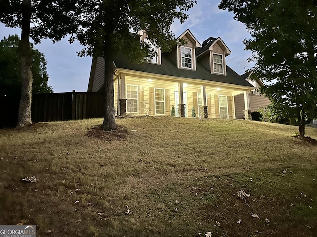 cape cod home with a lawn