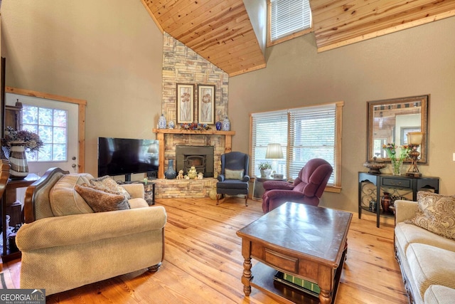 living room featuring high vaulted ceiling, light wood-type flooring, a fireplace, and wood ceiling