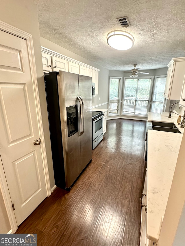 kitchen featuring appliances with stainless steel finishes, dark wood-type flooring, ceiling fan, and white cabinets