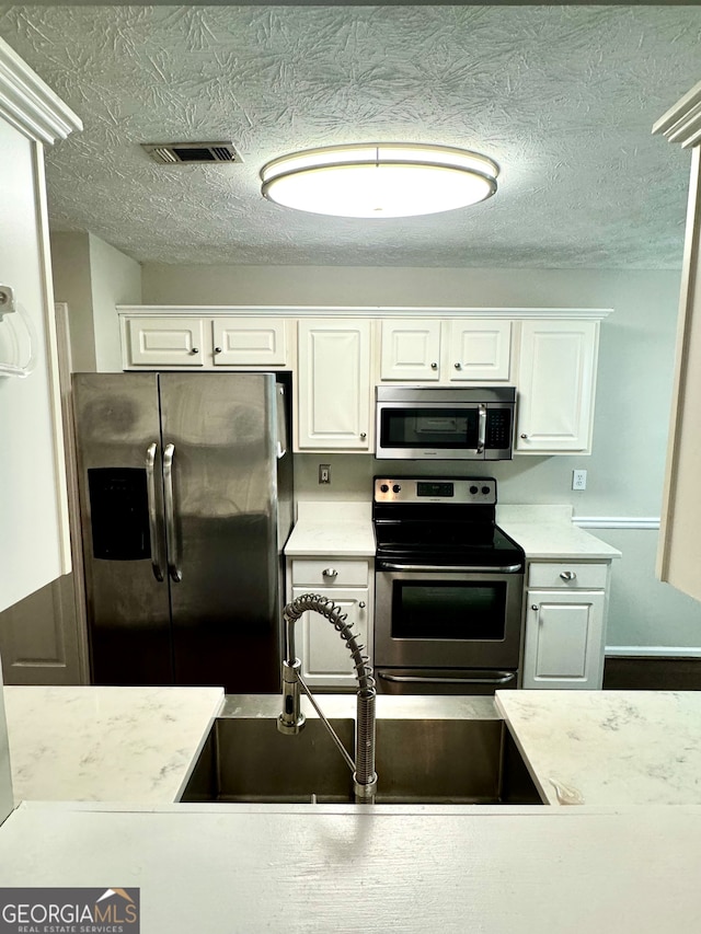 kitchen featuring stainless steel appliances, white cabinetry, and sink