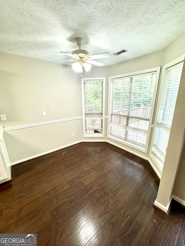 unfurnished room featuring ceiling fan, dark hardwood / wood-style floors, and a textured ceiling