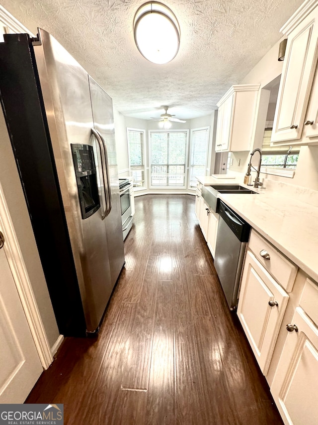 kitchen featuring appliances with stainless steel finishes, light stone counters, ceiling fan, dark hardwood / wood-style floors, and sink