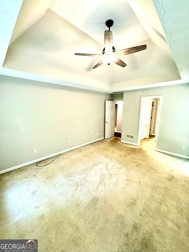 unfurnished bedroom featuring a tray ceiling, ceiling fan, and light colored carpet