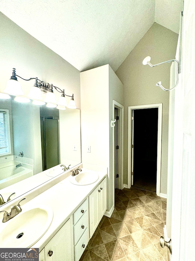 bathroom with vanity, vaulted ceiling, a textured ceiling, and separate shower and tub