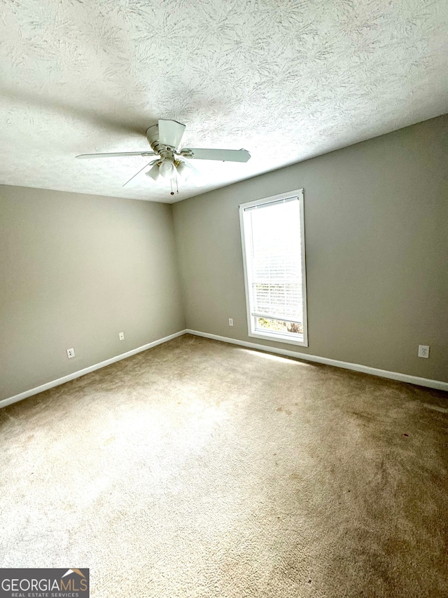 carpeted empty room featuring ceiling fan and a textured ceiling