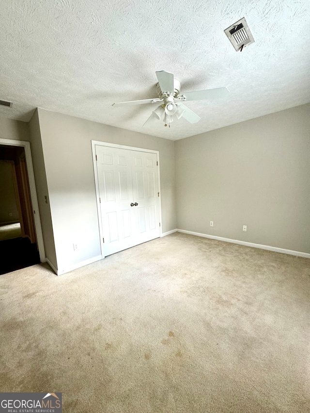 unfurnished bedroom featuring ceiling fan, a textured ceiling, a closet, and carpet