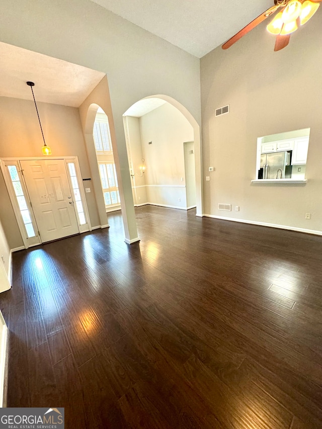 foyer entrance with high vaulted ceiling, a textured ceiling, ceiling fan, and dark hardwood / wood-style flooring