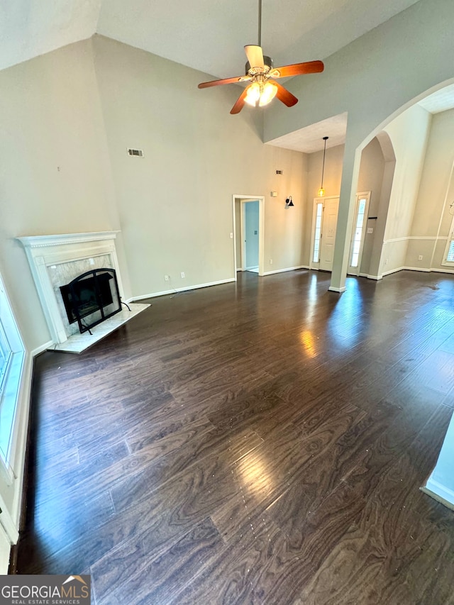 unfurnished living room with ceiling fan, a fireplace, dark wood-type flooring, and high vaulted ceiling