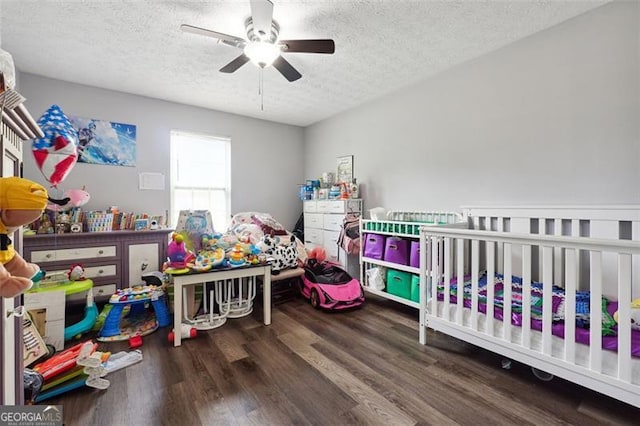 bedroom featuring ceiling fan, a nursery area, a textured ceiling, and hardwood / wood-style floors