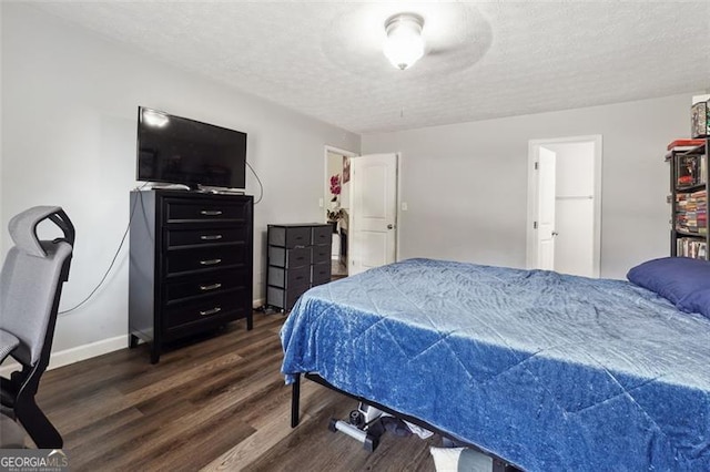 bedroom featuring a spacious closet, dark hardwood / wood-style flooring, and a textured ceiling