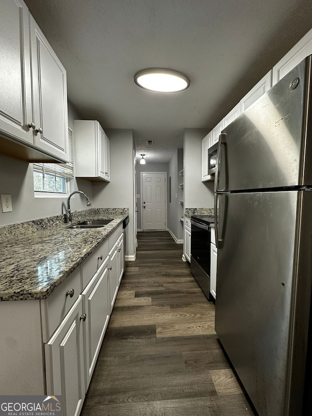 kitchen with white cabinetry, appliances with stainless steel finishes, dark wood-type flooring, light stone counters, and sink