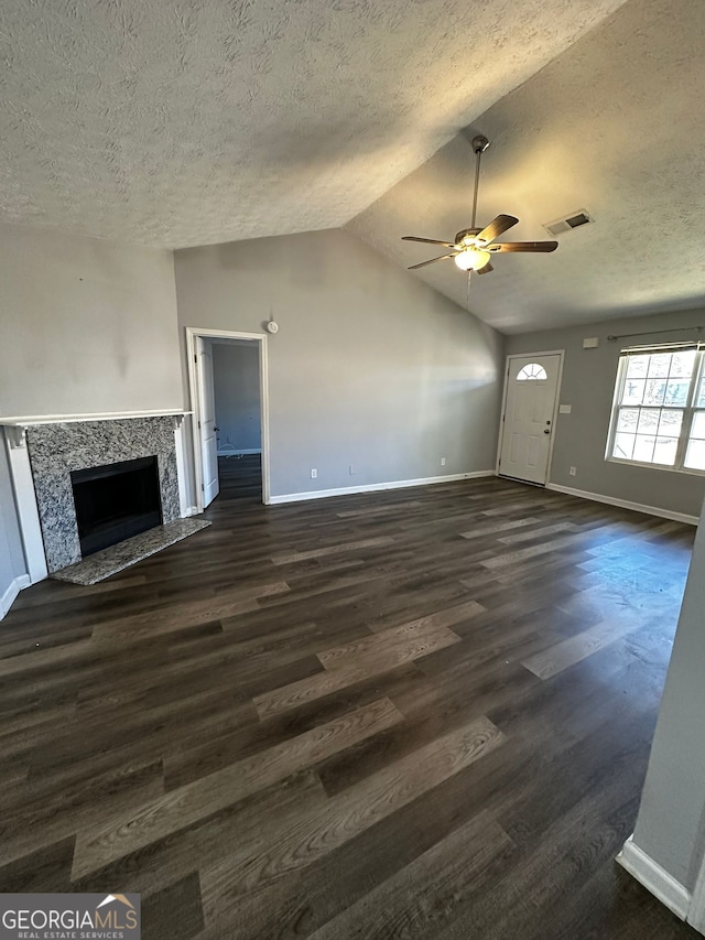 unfurnished living room featuring a textured ceiling, a high end fireplace, lofted ceiling, dark hardwood / wood-style flooring, and ceiling fan