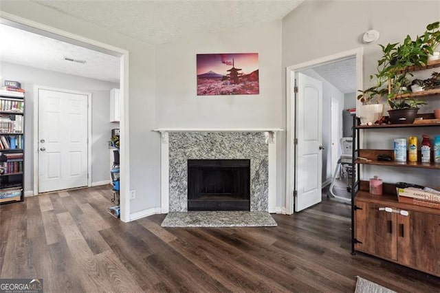 living room featuring a textured ceiling, dark hardwood / wood-style flooring, and a fireplace