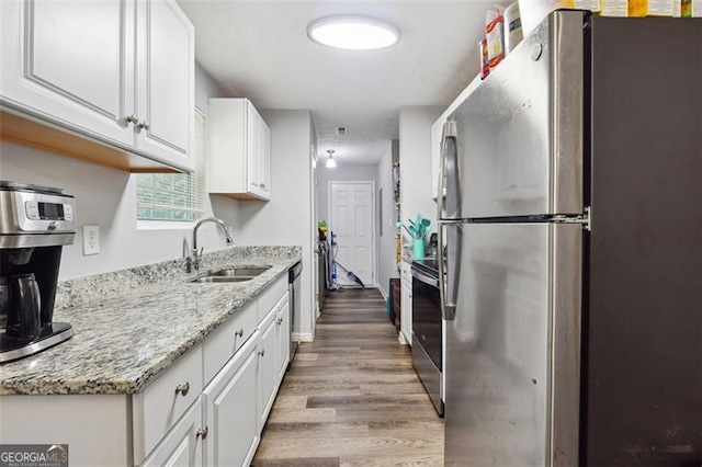 kitchen with light stone counters, sink, white cabinets, and stainless steel appliances