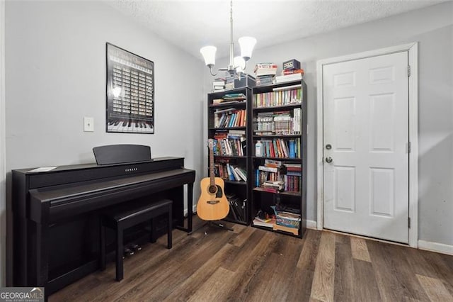 miscellaneous room with dark wood-type flooring, a textured ceiling, and an inviting chandelier