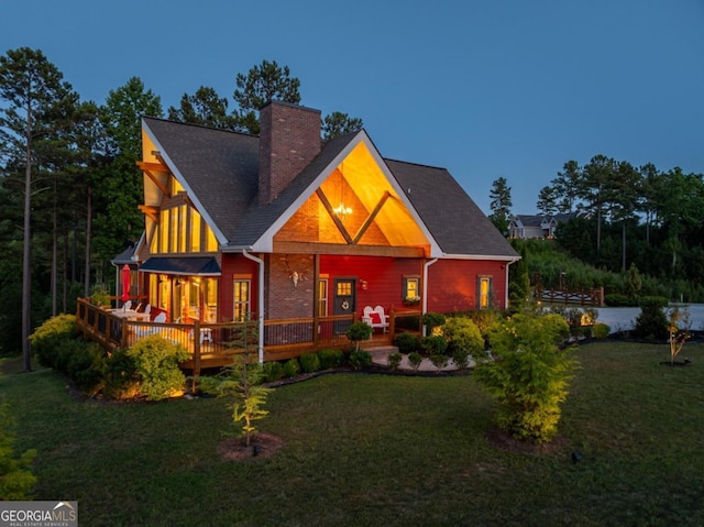 back of property featuring a wooden deck and a yard