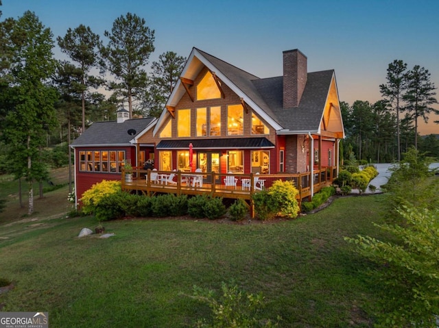 back house at dusk with a yard and a deck