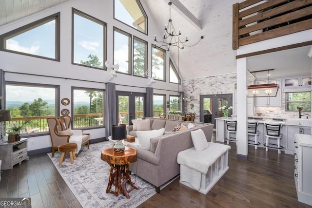 living room with french doors, an inviting chandelier, dark hardwood / wood-style flooring, and high vaulted ceiling