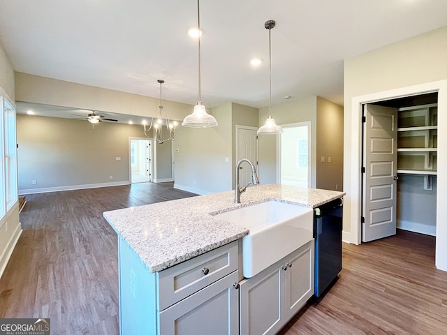 kitchen featuring a center island with sink, dishwasher, dark wood-type flooring, and decorative light fixtures