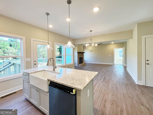 kitchen featuring a fireplace, a sink, visible vents, light wood-type flooring, and dishwasher