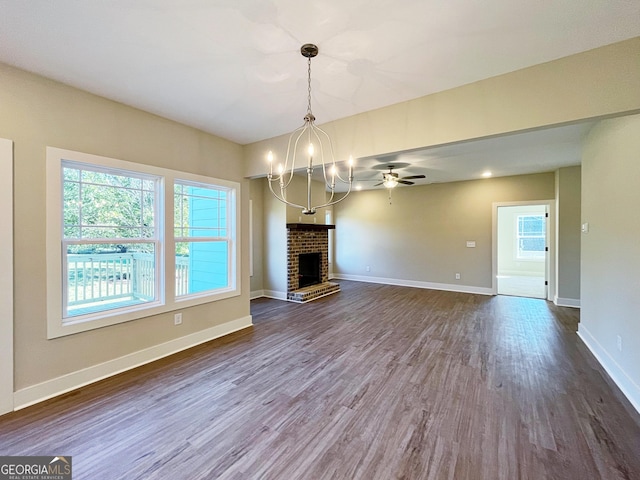 unfurnished living room featuring plenty of natural light, dark wood-type flooring, a brick fireplace, and baseboards