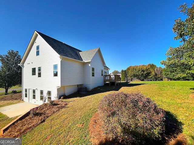 view of home's exterior with central AC unit, a lawn, and a wooden deck