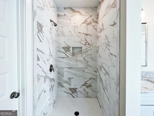 full bathroom featuring a tile shower and vanity