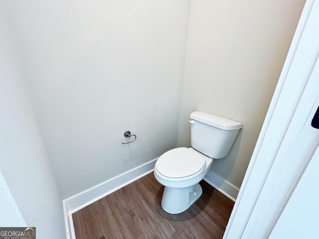 bathroom with toilet, baseboards, and wood finished floors