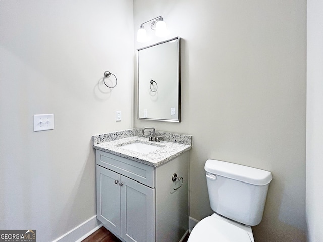 bathroom featuring toilet, vanity, and baseboards