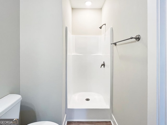 bathroom featuring a shower, wood-type flooring, and toilet