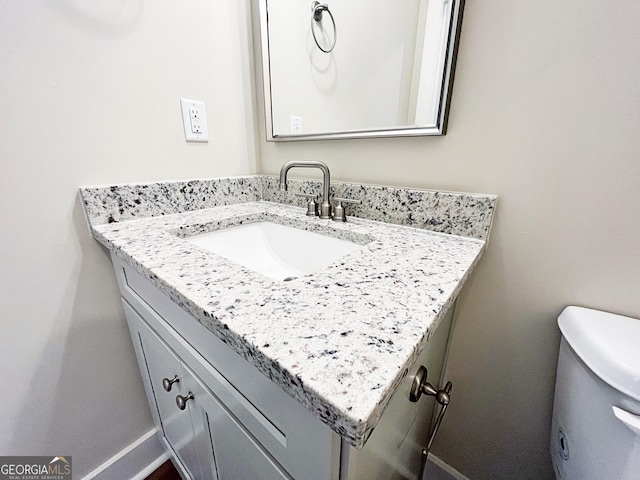 half bathroom with vanity and baseboards