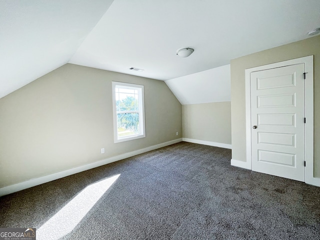 bonus room featuring vaulted ceiling and dark colored carpet