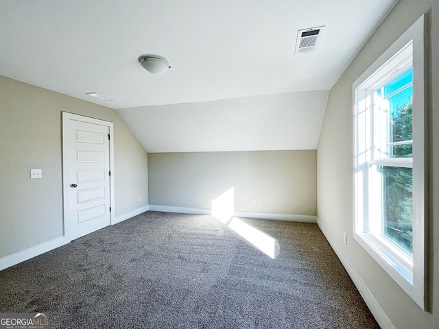 additional living space featuring vaulted ceiling, carpet flooring, visible vents, and baseboards