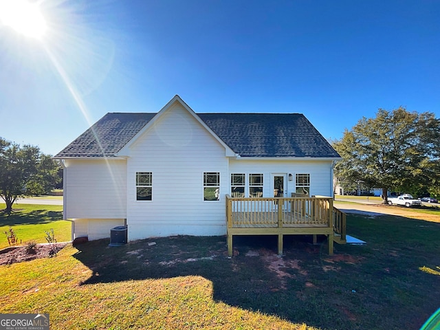 back of property with roof with shingles, a lawn, and a wooden deck