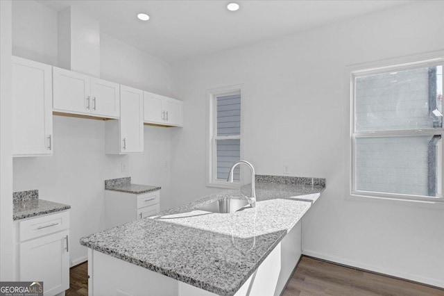 kitchen featuring kitchen peninsula, dark hardwood / wood-style flooring, white cabinets, and sink