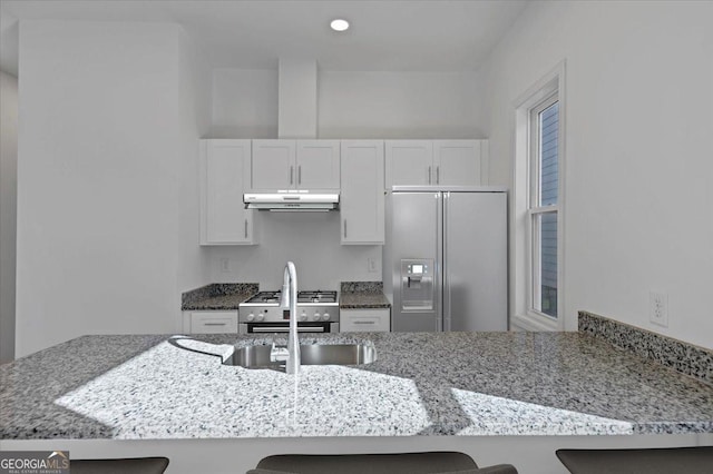 kitchen with a breakfast bar, kitchen peninsula, stainless steel appliances, and white cabinetry