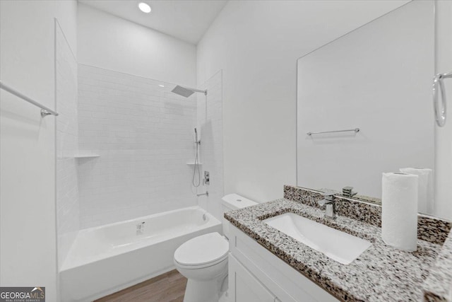 full bathroom featuring hardwood / wood-style floors, vanity, toilet, and tiled shower / bath