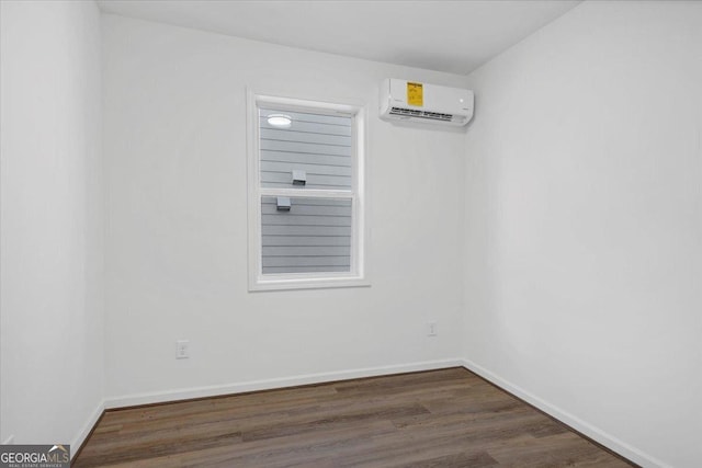 unfurnished room with a wall unit AC and dark hardwood / wood-style flooring