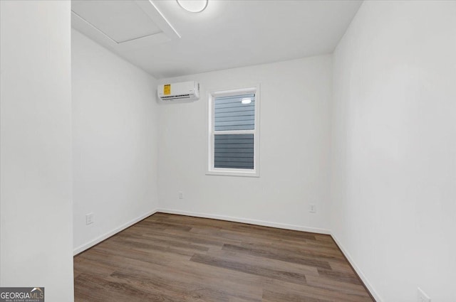 spare room featuring a wall unit AC and dark wood-type flooring