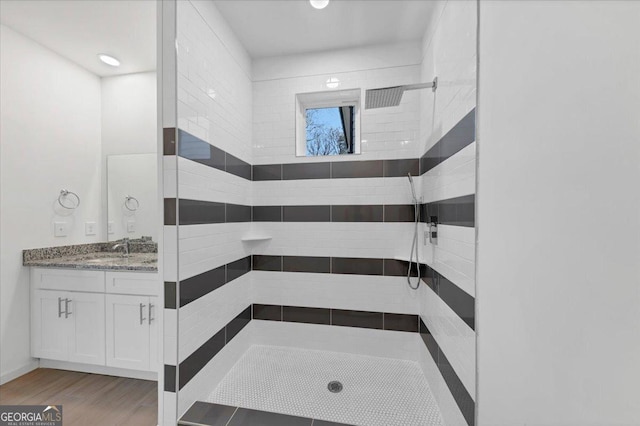 bathroom featuring a tile shower, vanity, and hardwood / wood-style flooring