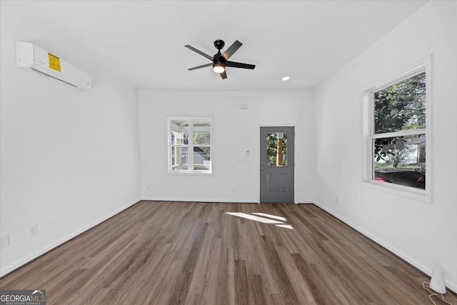 empty room featuring ceiling fan, dark hardwood / wood-style flooring, and a wall mounted AC