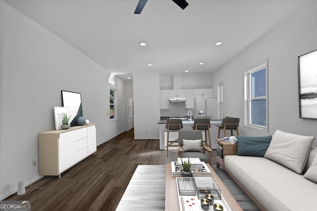 living room with plenty of natural light, ceiling fan, sink, and dark wood-type flooring