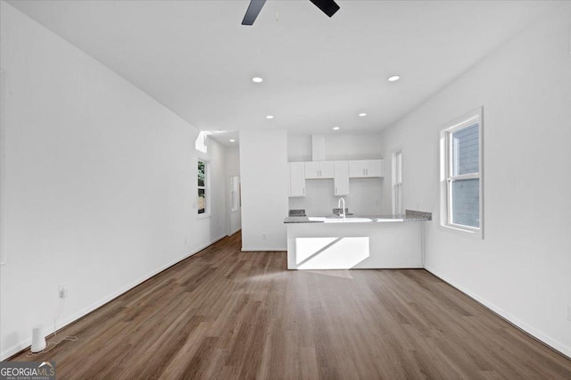 unfurnished living room with ceiling fan, sink, and dark wood-type flooring